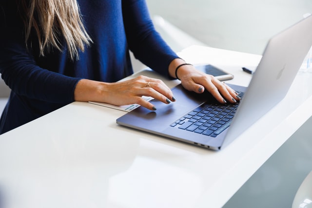 White woman's hands typing on a laptop