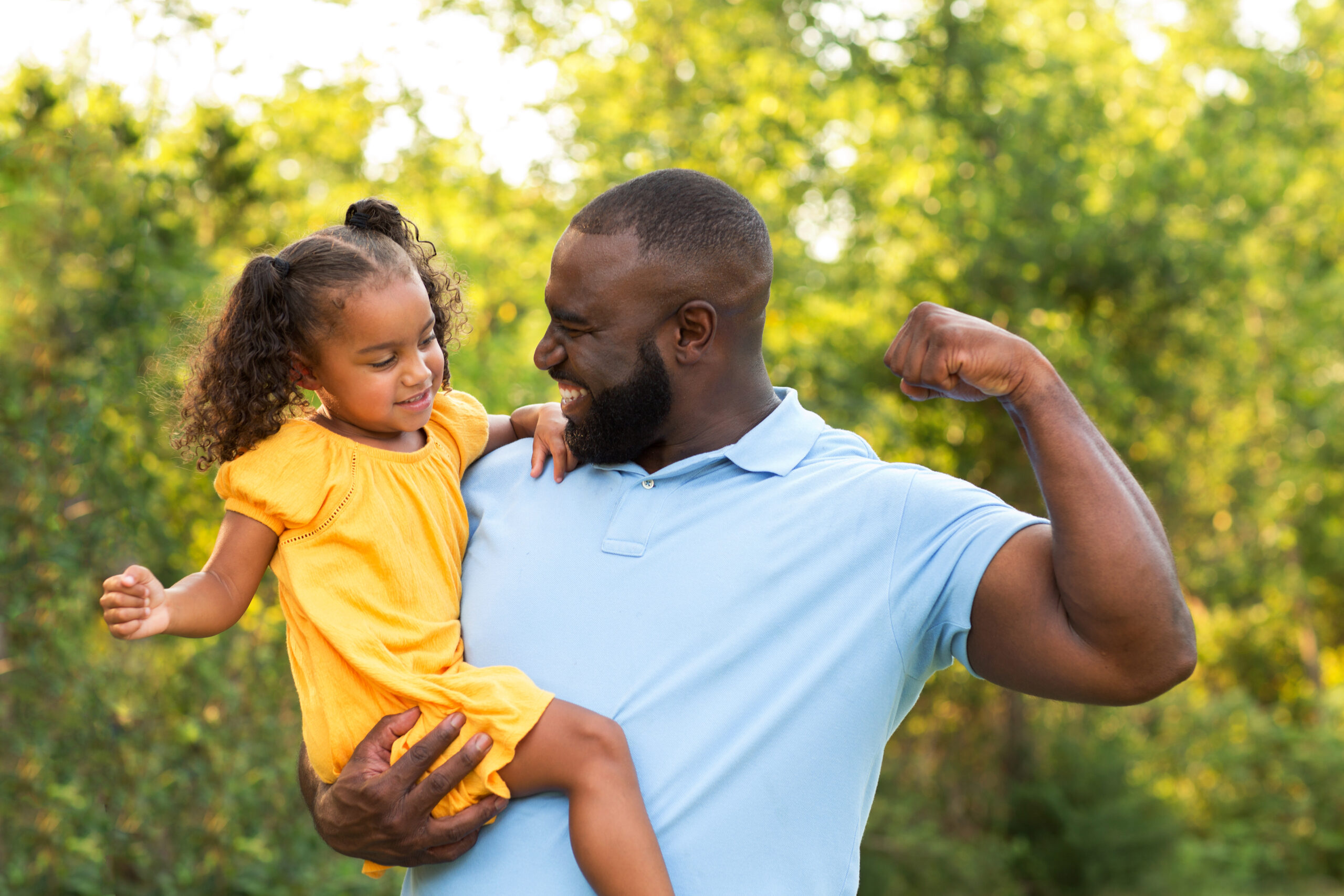 Black father holding his daughter outside