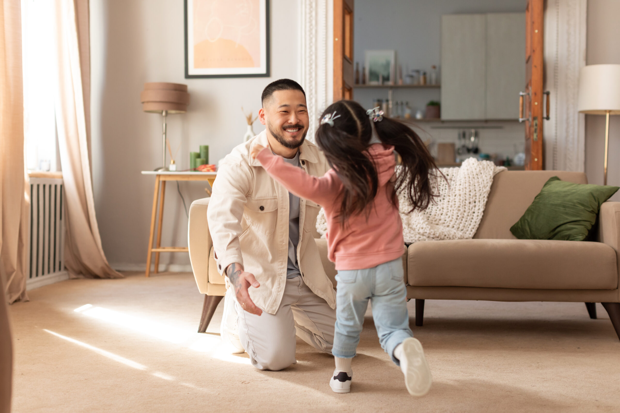 Korean daughter running toward father in sunny room