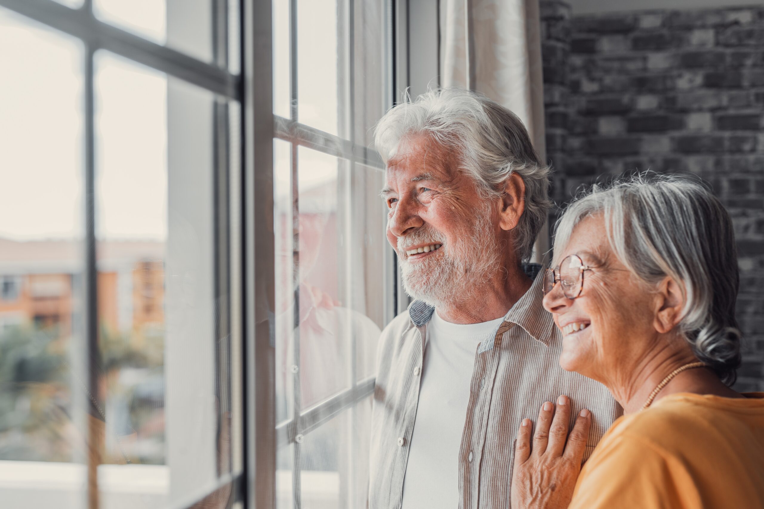 Senior white couple looking out a window